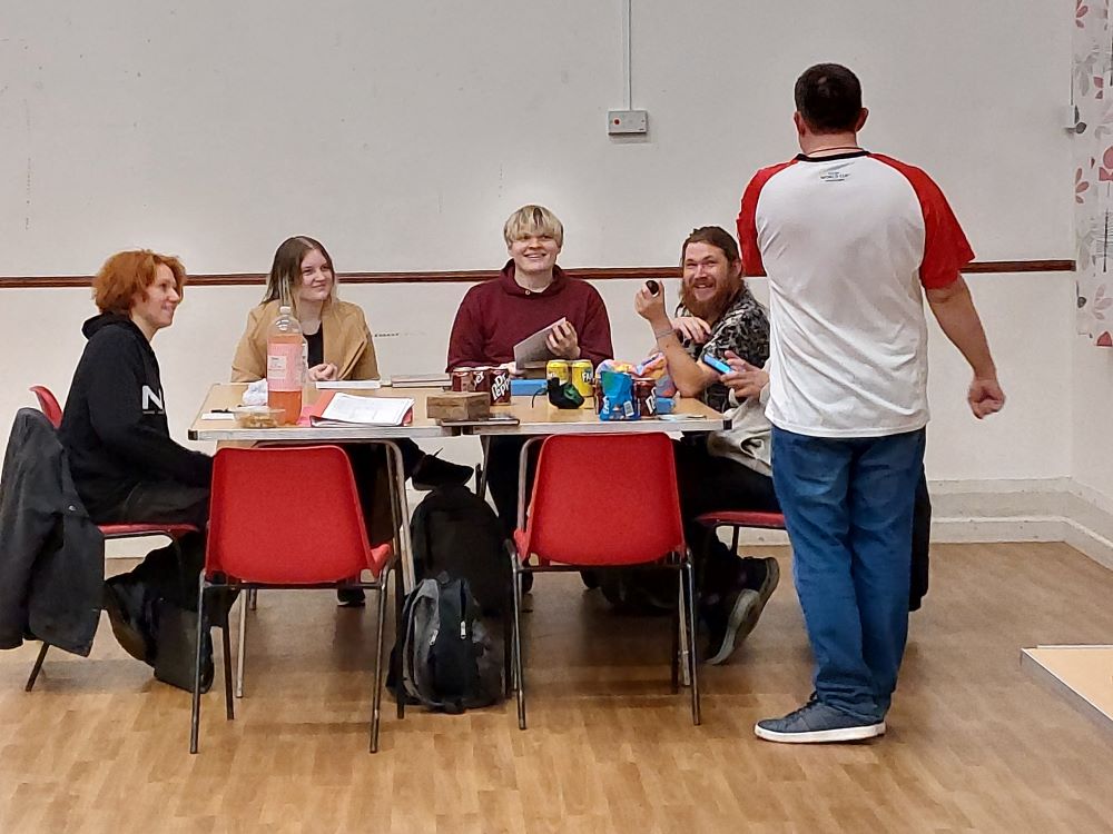People sat round table playing 1 stood